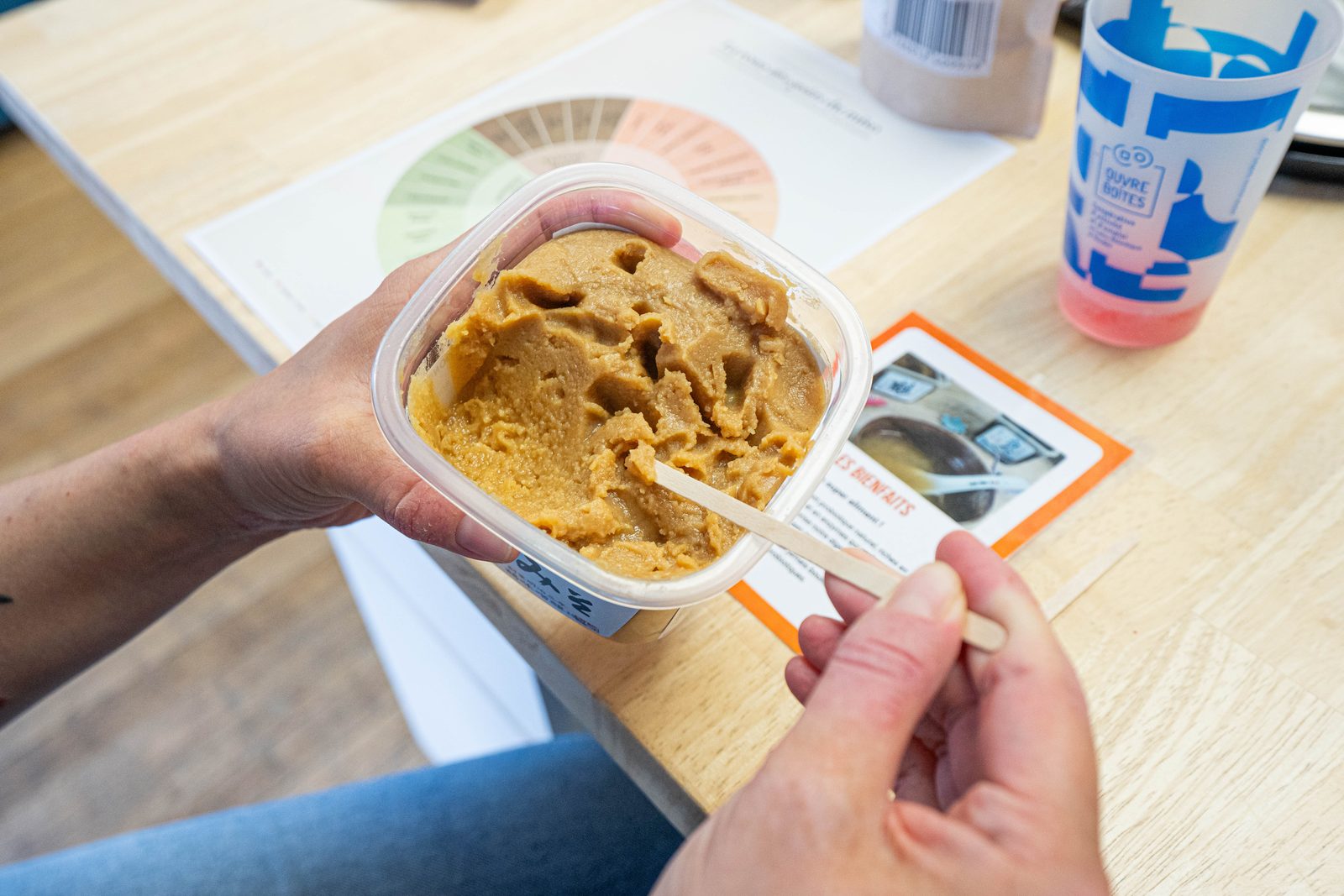 Dégustation de miso : une main tient un pot de miso ambré avec une spatule en bois